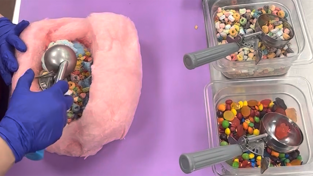 Woman scooping ice cream into a hollowed out piece of cotton candy.